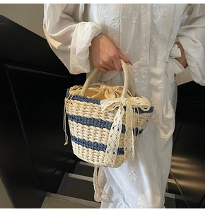 Detail of hand-woven straw bucket bag with blue stripes and lace bow decoration