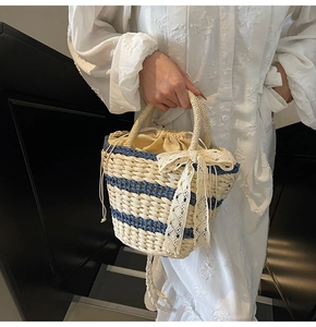 Detail of striped straw bucket bag featuring lace bow and beige drawstring closure