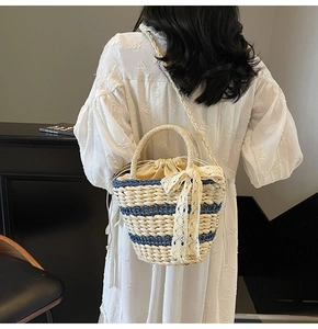 Detail of woven straw bucket bag with blue stripes and elegant lace bow decoration