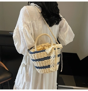 Detail of woven straw bucket bag featuring navy stripes, lace bow, and drawstring liner