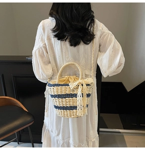 Detail of woven straw bucket bag with blue stripes and elegant lace bow accessory