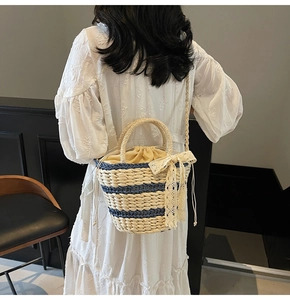 Detail of hand-woven straw bucket bag featuring nautical stripes and lace bow detail