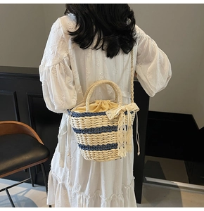Detail of woven straw bucket bag with blue stripes and decorative lace bow on the side