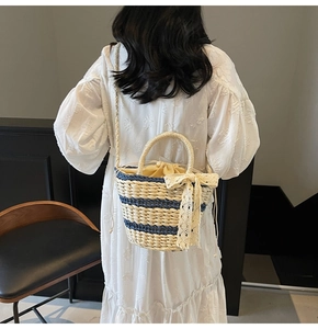 Detail of woven straw bucket bag with blue stripes, lace bow and drawstring lining