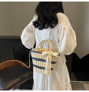 Detailed close-up of straw bucket bag with blue stripes and elegant lace bow decoration