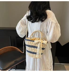 Detail of woven straw bucket bag with blue stripes and delicate lace bow on model back