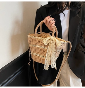 Detail of straw woven bucket bag featuring elegant white lace bow and drawstring inner bag