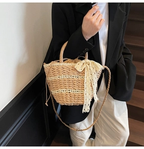 Detail of hand-woven straw bucket bag with delicate beige lace bow and drawstring liner