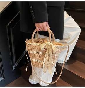 Detail of woven straw bucket bag with a lace bow and drawstring liner on wooden steps