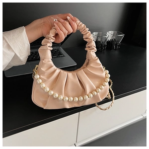 Close-up of beige ruched cloud bag featuring elegant pearl chain and soft texture