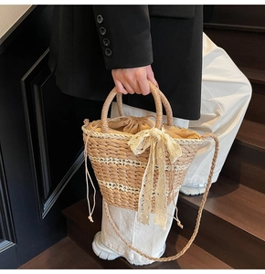 Detail of woven straw bucket bag with lace bow and drawstring liner on stairs