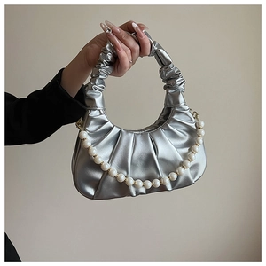Close-up of silver pleated cloud bag with metallic finish and decorative pearl chain strap