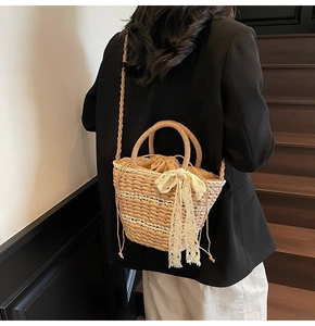Detailed macro view of woven straw bucket bag with delicate white lace bow accessory