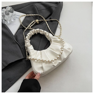 Detail of cream white pleated cloud bag with pearl handle and metal chain strap on blazer