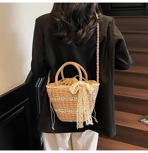 Detail of woven straw bucket bag with lace bow and drawstring liner on a female model