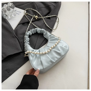 Close-up of light blue pleated cloud bag featuring pearl chain and gold metal strap