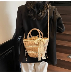 Detail of woven straw bucket bag with white lace bow and drawstring lining shown on model
