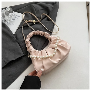 Detail of light pink pleated cloud bag with pearl handle and golden chain on grey suit