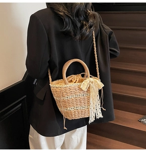 Detail of hand-woven straw bucket bag with white lace bow and drawstring closure