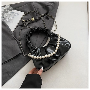 Detail of black pleated cloud bag featuring pearl handle and detachable gold chain strap