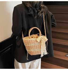 Detail of straw woven bag with white lace bow and drawstring closure for women