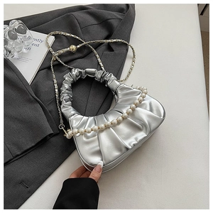 Detail of silver pleated cloud bag featuring pearl handle and metallic chain strap