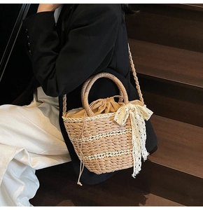 Detailed close-up of woven straw bucket bag with white lace bow and drawstring inner bag