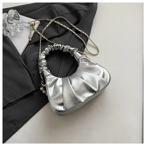 Detail of silver pleated cloud bag featuring metallic finish and gold pearl chain