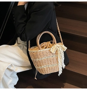 Detail of woven straw bucket bag with white lace bow and drawstring liner