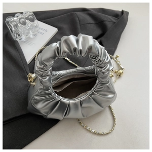 Detail view of silver pleated cloud bag with metallic texture and gold chain strap