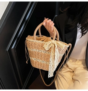 Close-up of woven straw bucket bag featuring a large lace bow and drawstring lining