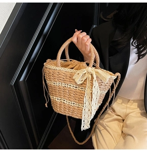 Detail of woven straw bucket bag featuring cream lace bow and drawstring closure