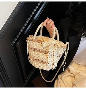 Close-up of woven straw bucket bag with white lace bow and drawstrings