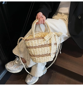 Detail of hand-woven straw bucket bag featuring a large lace bow and drawstring lining