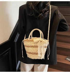 Detail of woven straw bucket bag with lace bow and drawstring inner bag on model