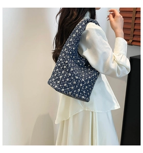 Close-up of denim tote bag featuring silver studs and white pearl accents with wide strap
