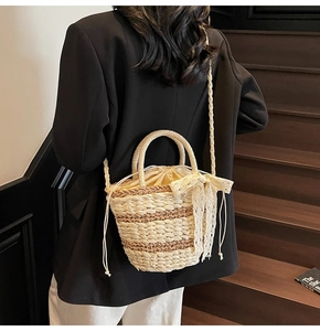 Detail of woven straw bucket bag with lace bow and drawstring liner on a black blazer