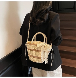 Detail of hand-woven straw bucket bag featuring a delicate lace bow and secure drawstring inner