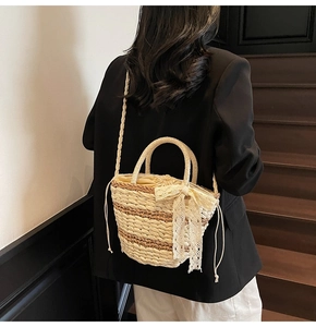Detail of woven straw bucket bag with lace bow and brown striped stitching accents