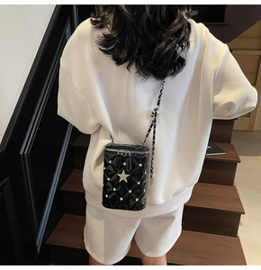 Détail du sac seau matelassé avec clous en étoile et bandoulière chaîne en cuir