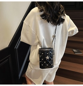 Détail du sac seau noir matelassé avec étoile argentée et bandoulière en chaîne