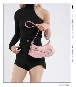 Detail of pink half-moon shoulder bag with leather texture and silver buckle straps