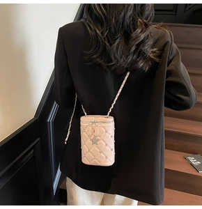 Détail du sac seau rose matelassé avec pendentif étoile et bandoulière en chaîne