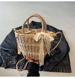 Detail of woven straw bucket bag with lace bow decoration and drawstring inner bag