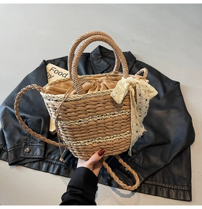 Close-up of woven straw bucket bag featuring lace bow detail and dual ring handles