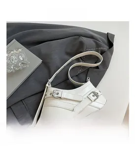 Detailed view of white PU leather crescent bag with buckle straps and silver hardware