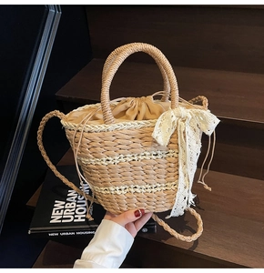 Detail of woven straw bucket bag with white lace bow and drawstring liner on wood steps