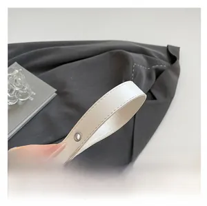 Detail of white leather shoulder strap with visible stitching and metal eyelets on bag