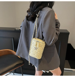 Détail du sac cylindre matelassé jaune avec pendentif étoile et chaîne en métal