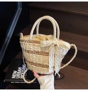 Close-up of woven straw bucket bag with lace bow detail and drawstring liner on wooden stairs